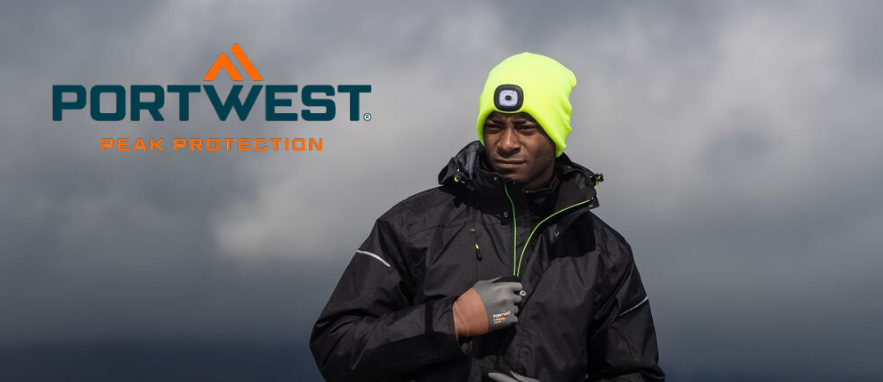 Afbeelding van een werker in zwarte werkkleding. De man draagt ​​handschoenen en een gele pet met een ingebouwde ledlamp. Op de achtergrond zijn donkere wolken en een mistig landschap te zien.