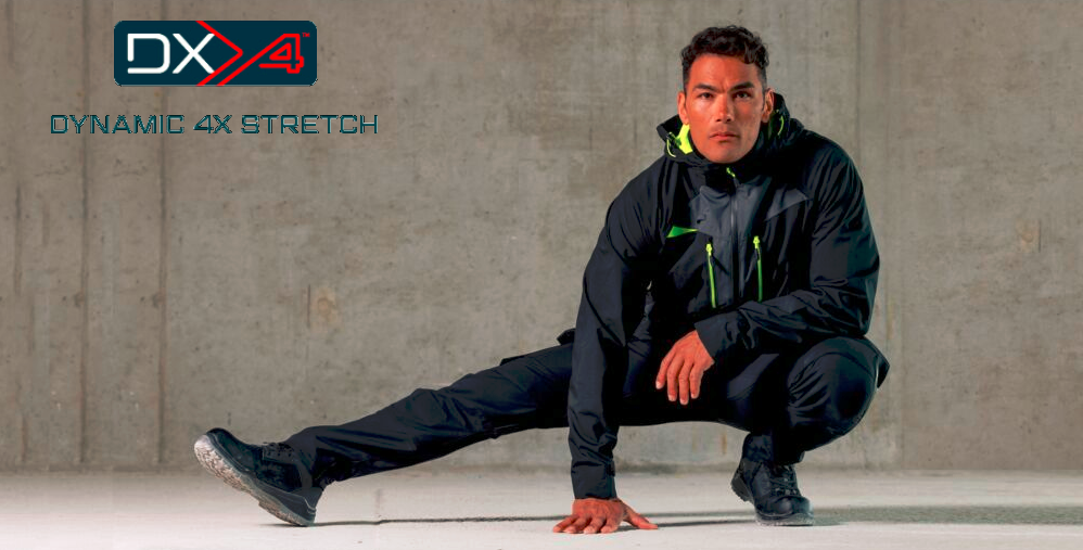 Man in het zwart, sportieve werkkleding met neonkleurige accenten, gehurkt voor een grijze betonnen muur. Linksboven staat het logo ‘DX4 Dynamic 4X Stretch’.