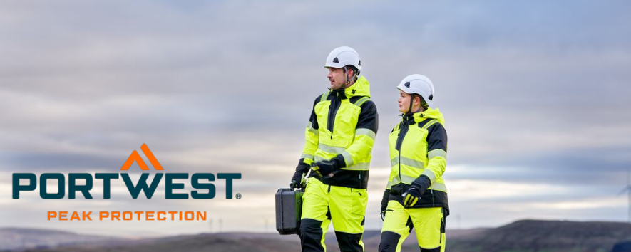 De afbeelding toont een man en een vrouw in gele werkkleding en witte veiligheidshelmen. Ze lopen over een grindpad. Op de achtergrond zijn heuvels en een blauwe lucht met wolken te zien. Het blauw-oranje Portwest-logo bevindt zich in de linkerbenedenhoek.