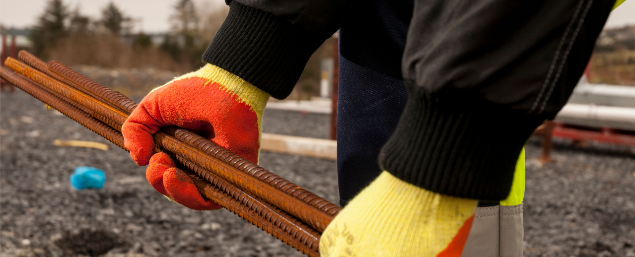 Modelafbeelding van de Fortis Grip A150 handschoen in geel/oranje werkend met wapening.