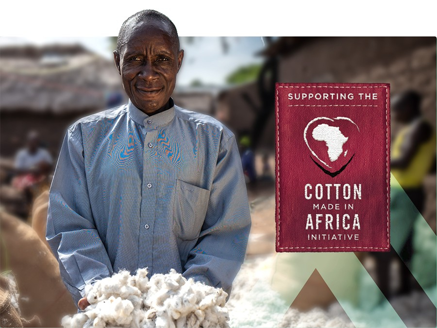 Afrikaanse boer draagt ​​een blauw shirt en presenteert een handvol katoen. Een dieprood bord met de tekst "Supporting the Cotton Made In Africa Initiative" bevindt zich in de rechterhelft van de afbeelding.