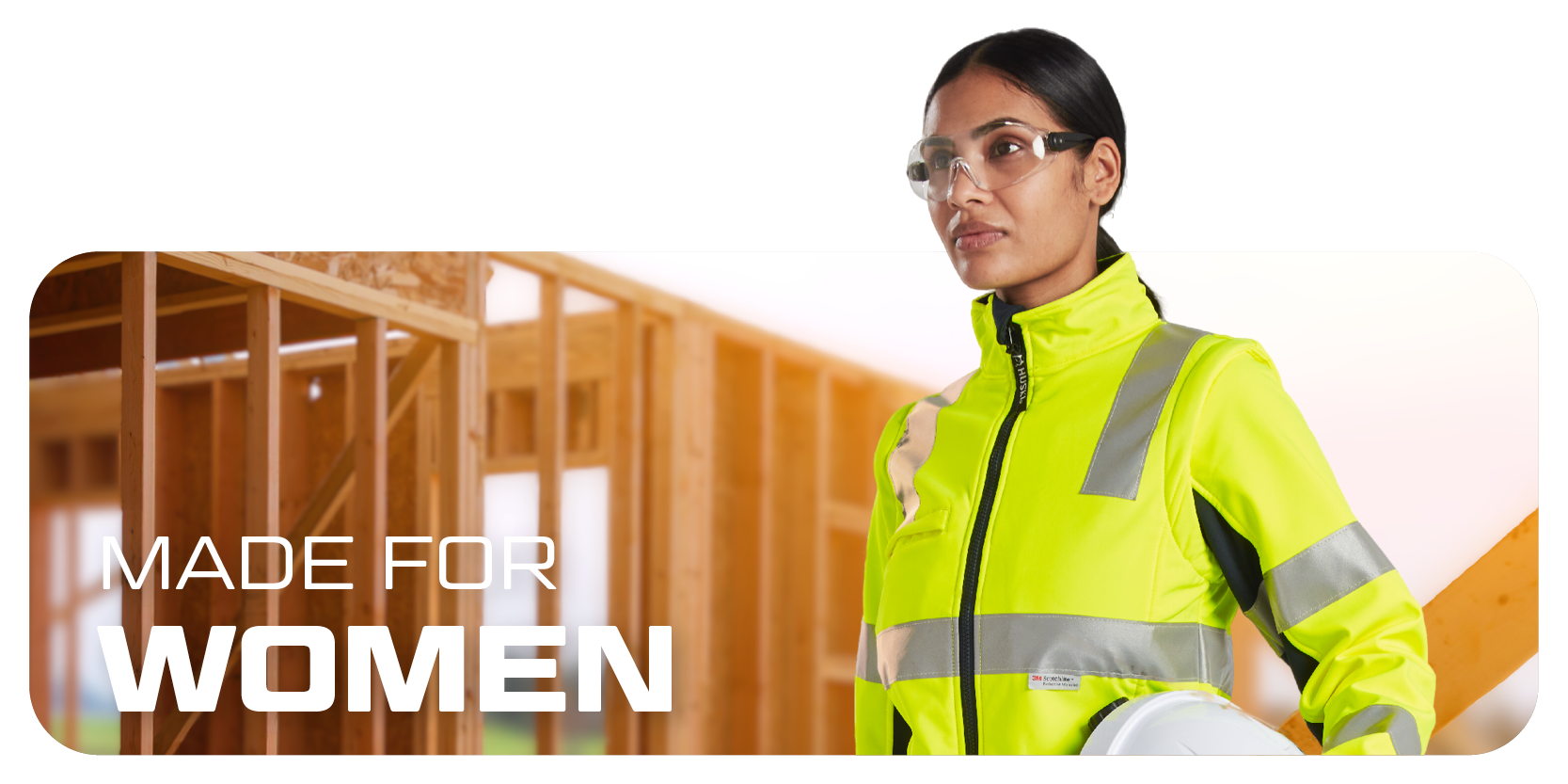 Dame met bril, helm en waarschuwingskleding, op de achtergrond houten wanden in paal- en balkconstructie.