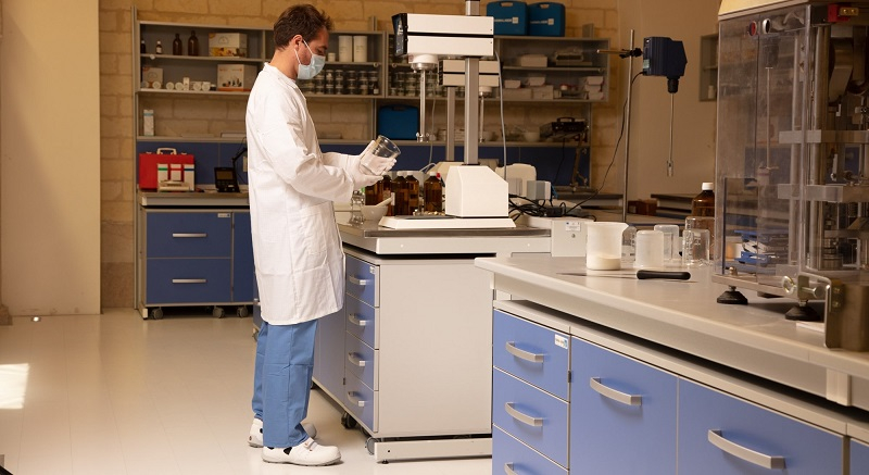 Laborant in witte jas en antistatische beschermende kleding aan het werk in het laboratorium met een gekoppelde koppeling aan de antistatische werkjas.